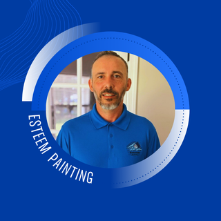 Professional portrait of a man in a blue polo shirt with Esteem Painting logo, set against a blue background, representing quality interior painting services.